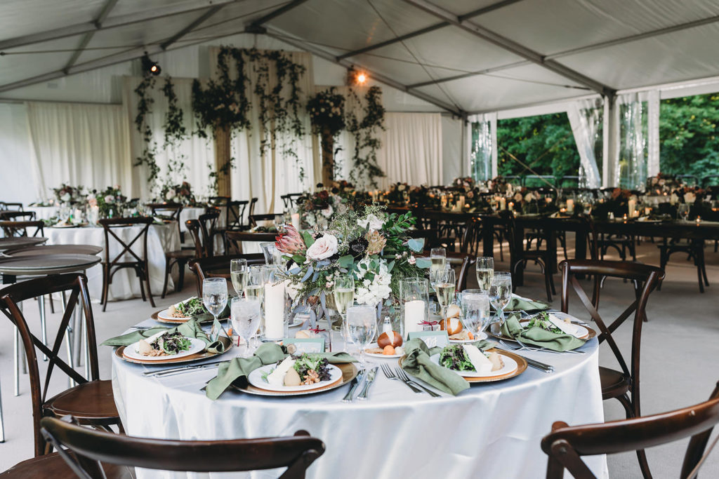 wide shot of inside of tent with lots of floral and pillars and candles at a Carmel Backyard Wedding