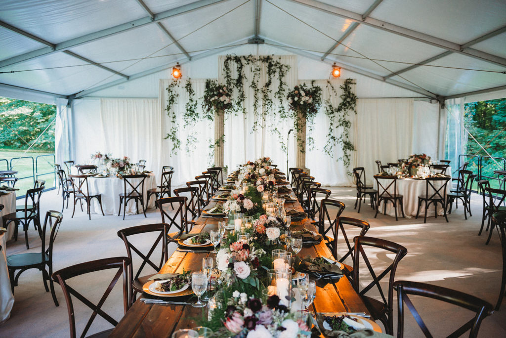 long wooden table leads to florals hanging from pillars at a Carmel Backyard Wedding ceremony