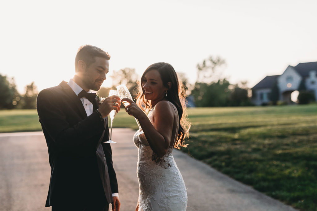 bride and groom prepare to toast and drink champagne at sunset during their Carmel Backyard Wedding