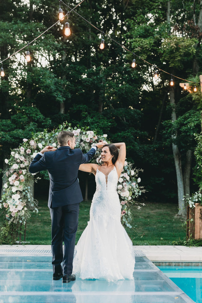 bride and groom first dance over a pool and with intertwining arms at their Carmel Backyard Wedding