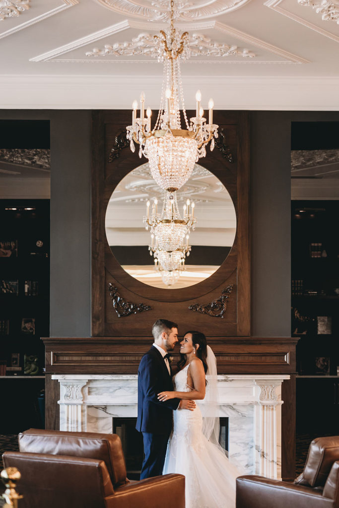 bride and groom hug and kiss in front of fireplace in hotel Carmichael