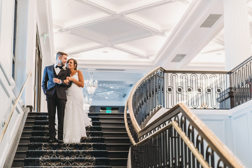 bride and groom walk down steps at Hotel Carmichael before their carmel backyard wedding