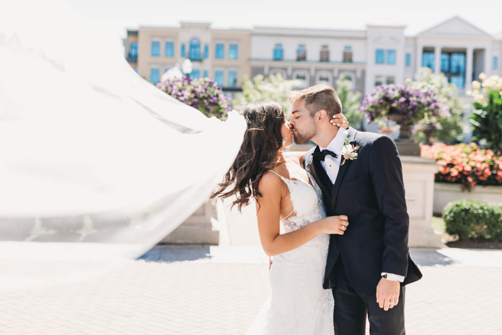 Wind holds bride's veil aloft outside the palladium before their carmel backyard wedding