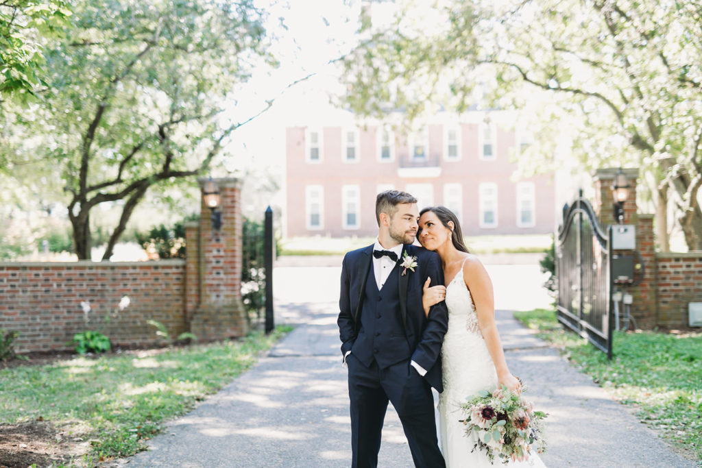 bride and groom posing in front of historic house at coxhall gardens before their carmel backyard wedding