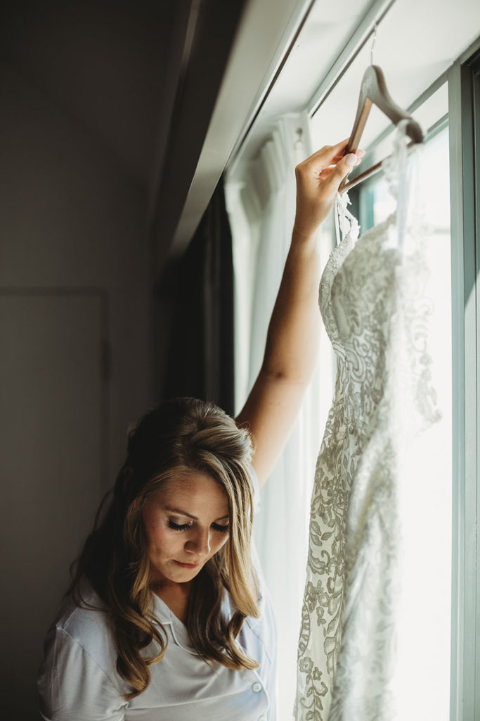 bridesmaid hangs up bride's wedding dress before her Indiana Roof Ballroom wedding