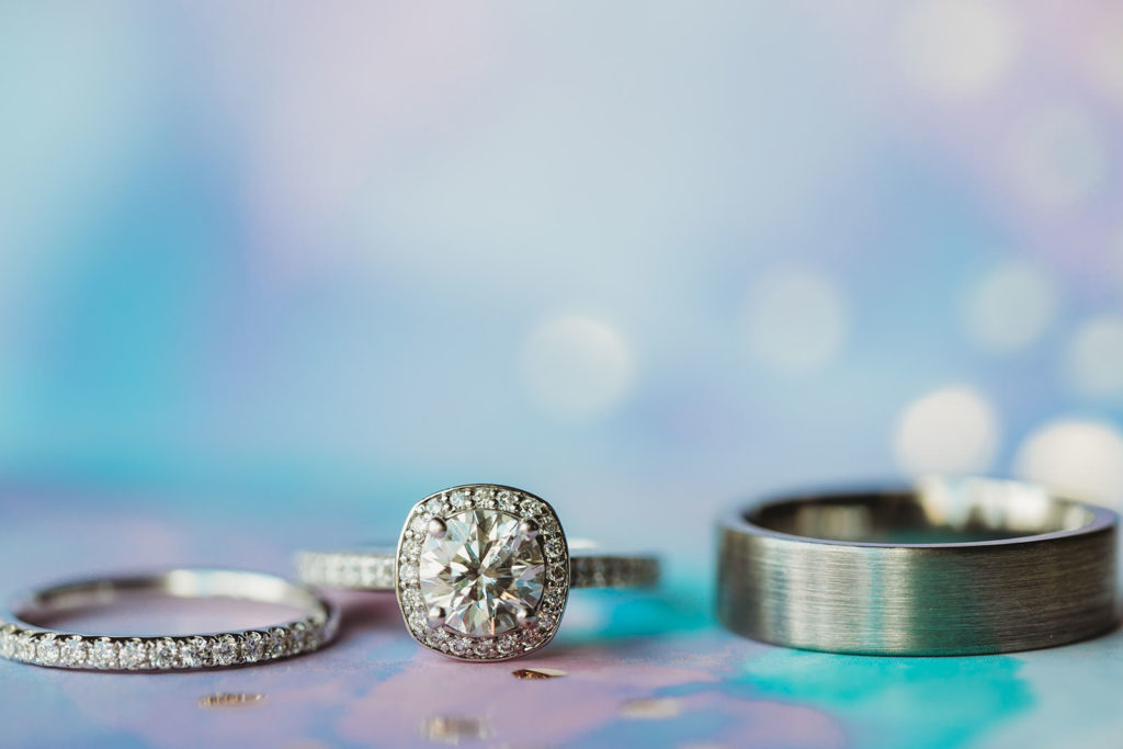 engagement ring and wedding bands with lots of bokeh behind and varying pastel colors for an Indiana Roof Ballroom wedding
