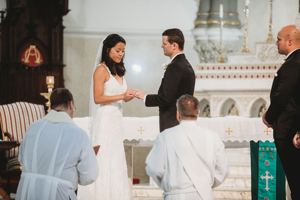 bride and groom exchange rings and vows in a wedding ceremony at St. John the Evangelist Catholic Church