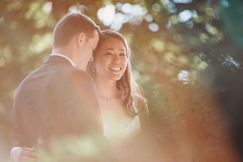 lens flare on camera while bride and groom hug in front of indiana statehouse