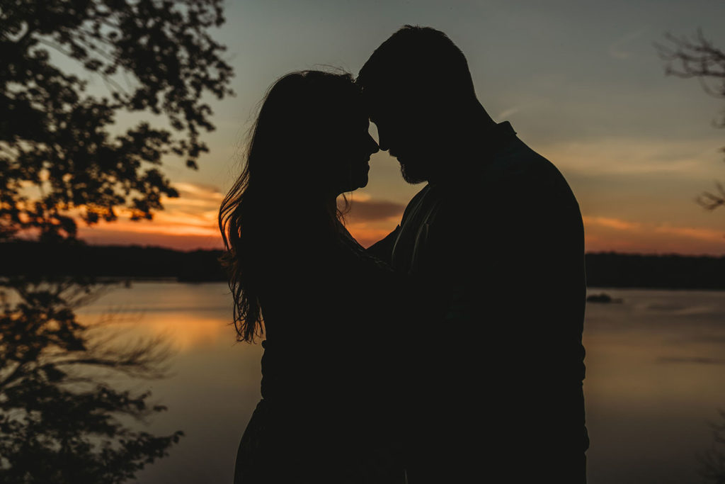 silhouettes of two people touching foreheads at sunset during their Indy Reservoir Engagement