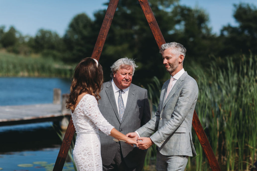 bride and groom are married in front of a-frame in front of pond at their traders point creamery wedding