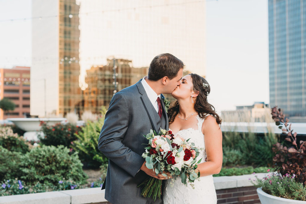bride and groom kiss on top of regions tower at a Regions Tower Wedding Celebration
