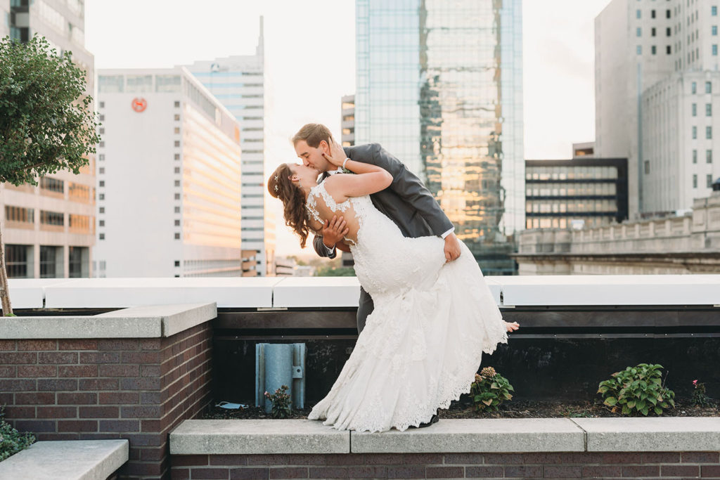 groom dips and kisses bride at a Regions Tower Wedding Celebration