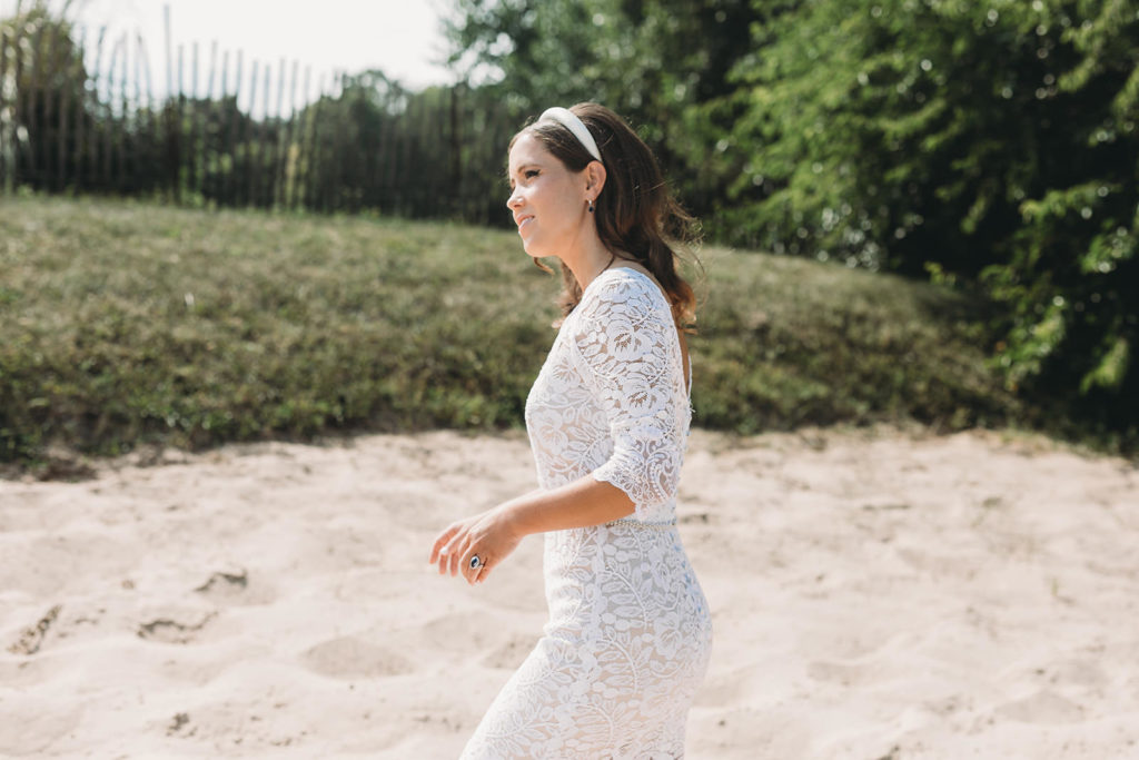 bride in white wedding gown walks across sand to see groom at her traders point creamery wedding