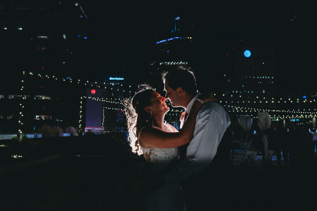 bride and groom dance at night with light bokeh behind them at a Regions Tower Wedding Celebration