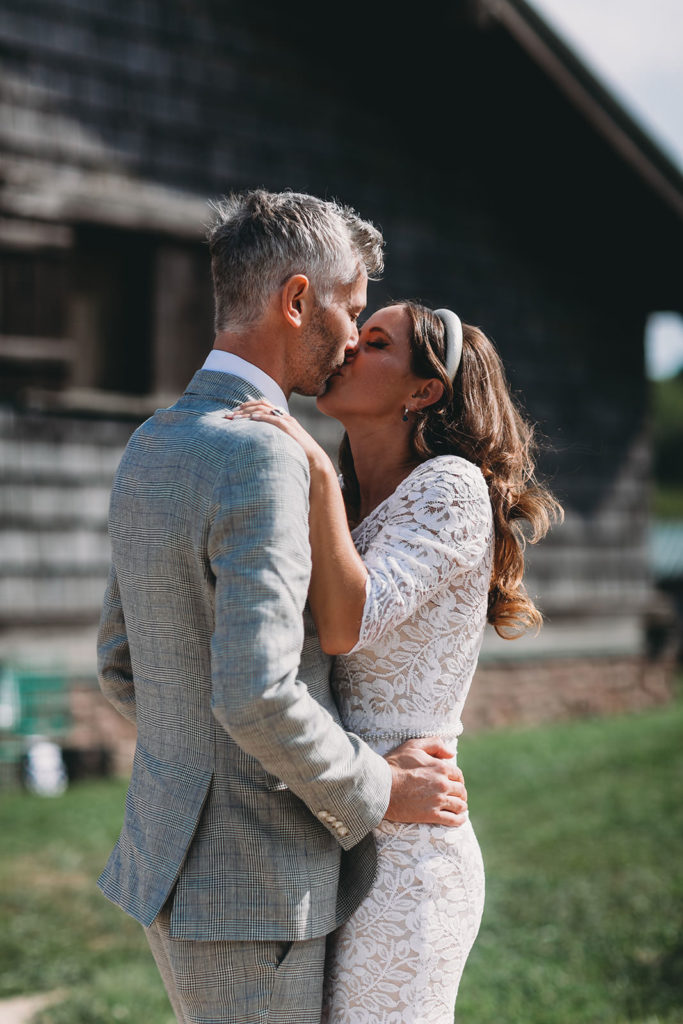 woman in white kisses man in gray suit during their traders point creamery wedding