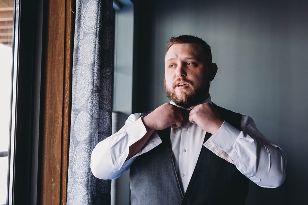 groom ties his bow tie at a 3 Fat Labs wedding