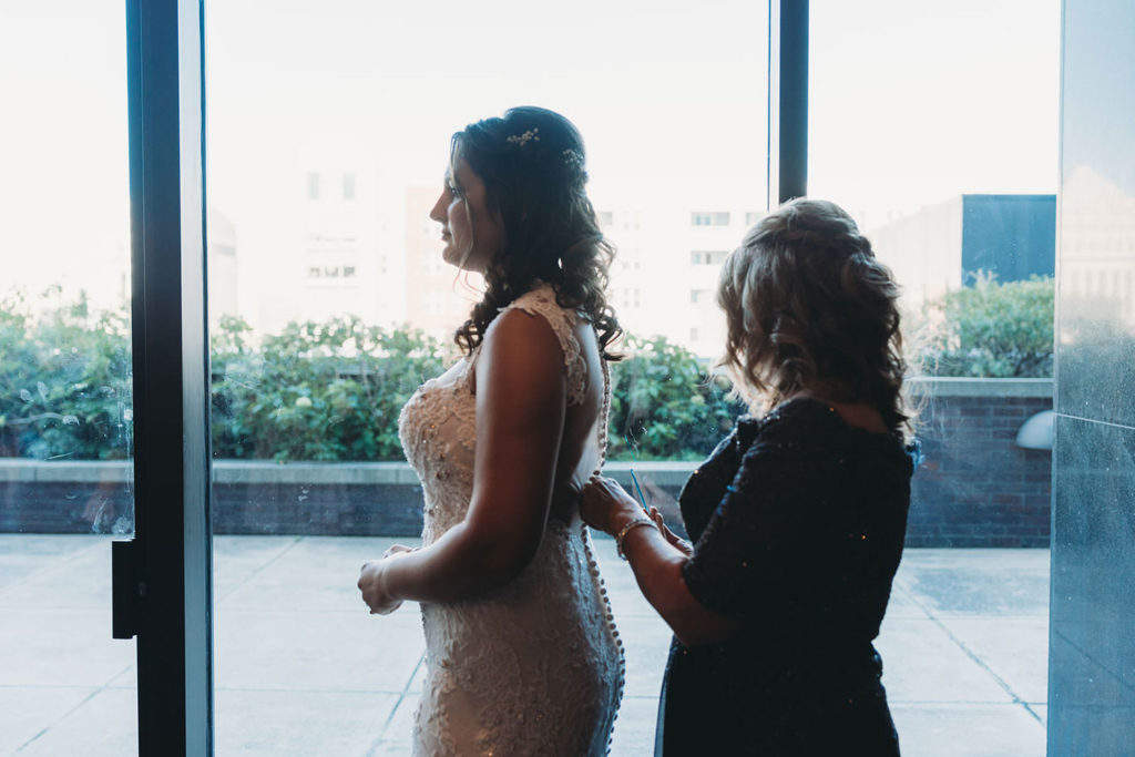mom helps bride into dress at a Regions Tower Wedding Celebration