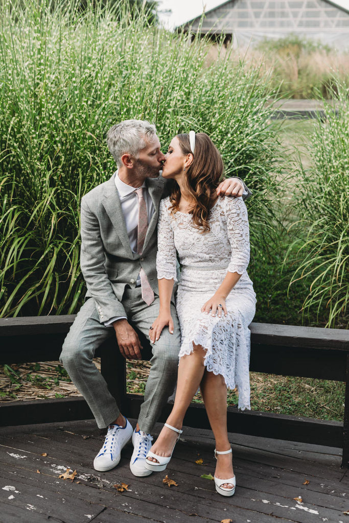 bride and groom sit on bench and kiss at their traders point creamery wedding