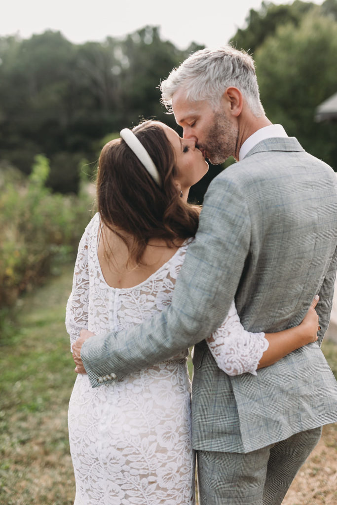 bride and groom walk and hug and kiss at a rustic zionsville wedding