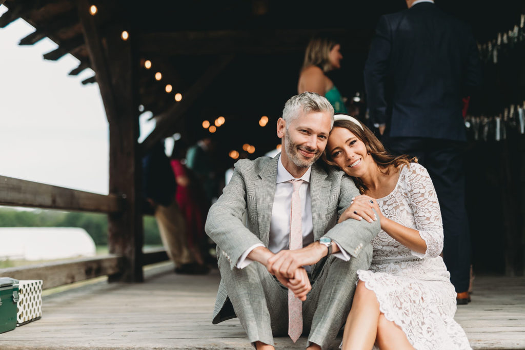 bride and groom sit on wooden steps during their traders point creamery wedding