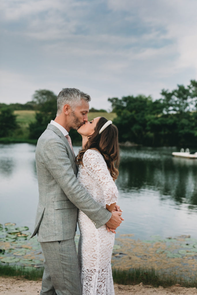 bride and groom kiss in front of pond at their traders point creamery wedding