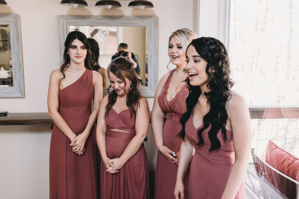 bridesmaids gasp as they see bride in wedding dress for first time at a 3 Fat Labs wedding