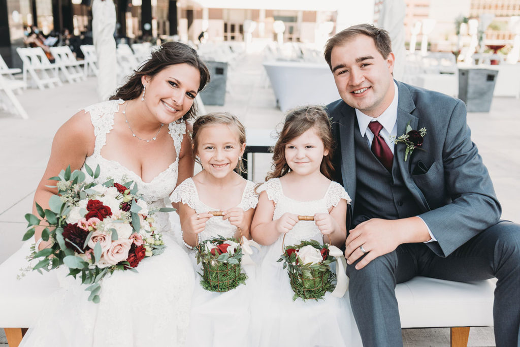 bride and groom sit with flower girls at a Regions Tower Wedding Celebration