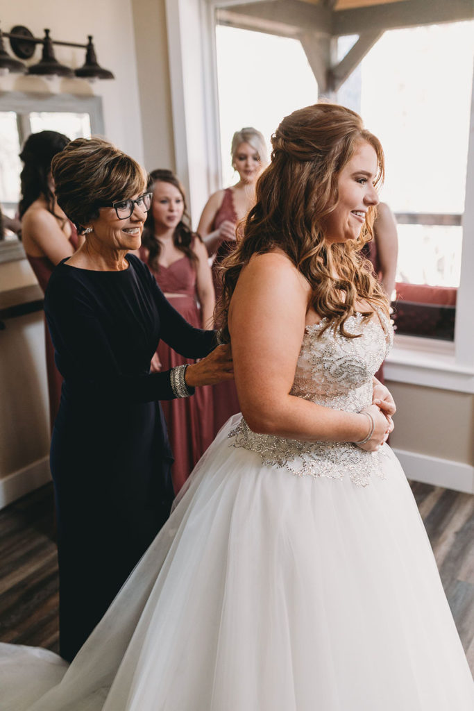 bride's mom helps her get into her wedding dress at a 3 Fat Labs wedding