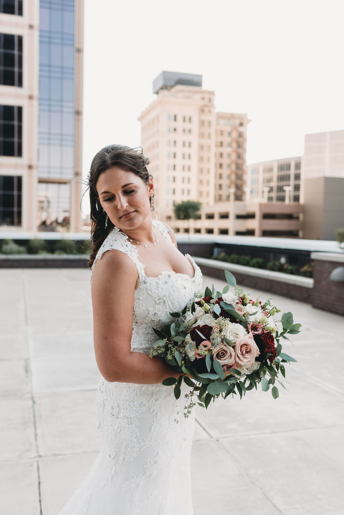 bride with bouquet on top of regions tower during her wedding celebration