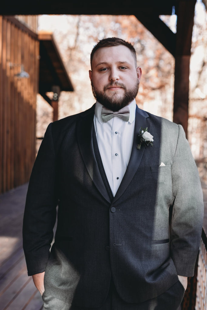 groom stands, half in light and half in shadow at a 3 fat labs wedding