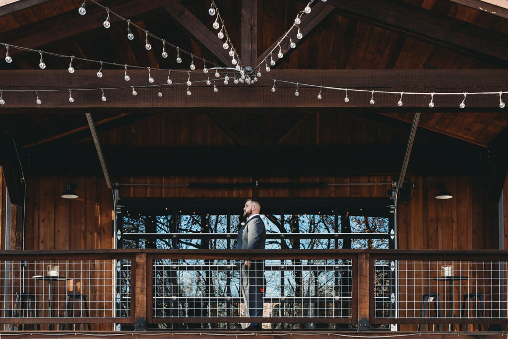 groom waiting for bride to approach in wide shot with string lights making leading lines to him at his 3 Fat Labs wedding