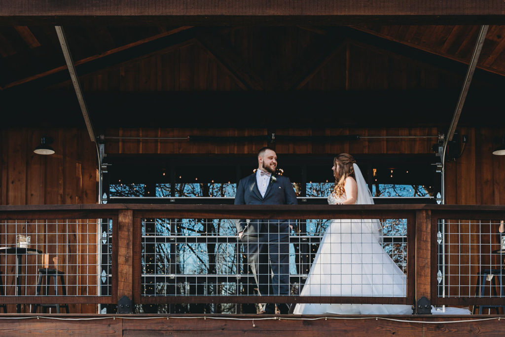 groom sees bride for first time on the deck behind the barn at their 3 Fat Labs wedding