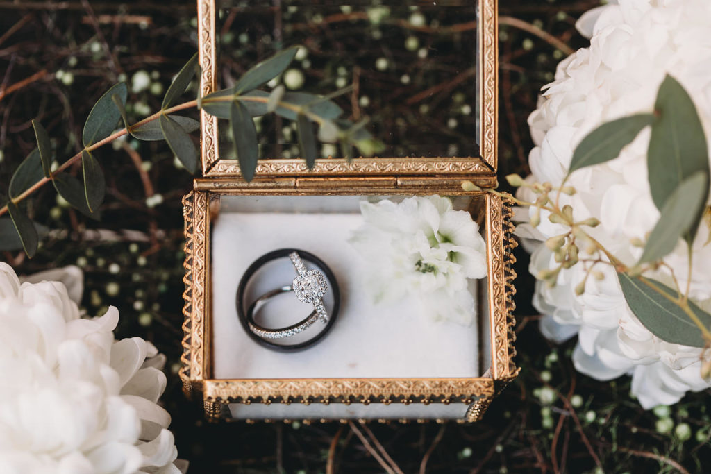 rings in a small gold box with glass sides inside a floral basket at a 3 Fat Labs wedding