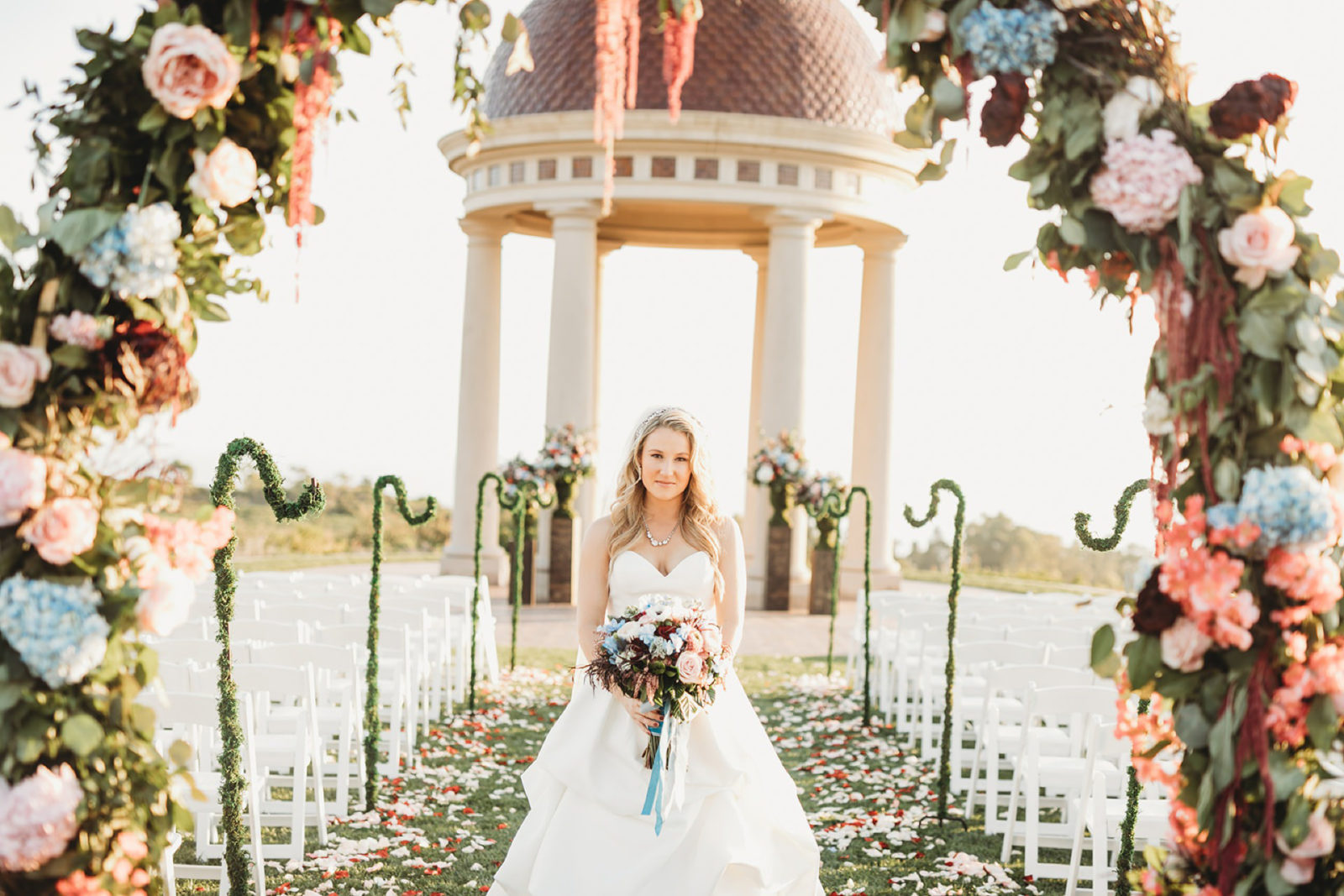 bride walking down aisle after wedding is over framed by floral arch at a pelican hill wedding