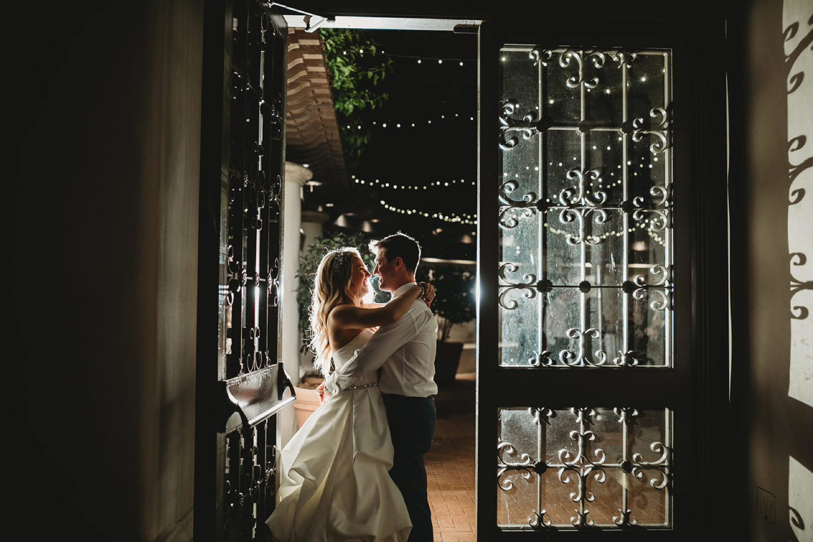 wide shot of bride and groom kissing in doorway at night at a pelican hill wedding