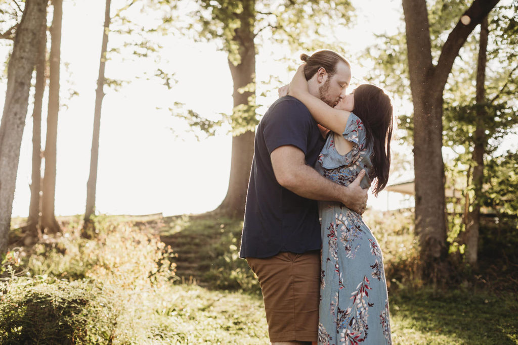 young engaged couple kiss in park at sunset during their Arbuckle Acres engagement session