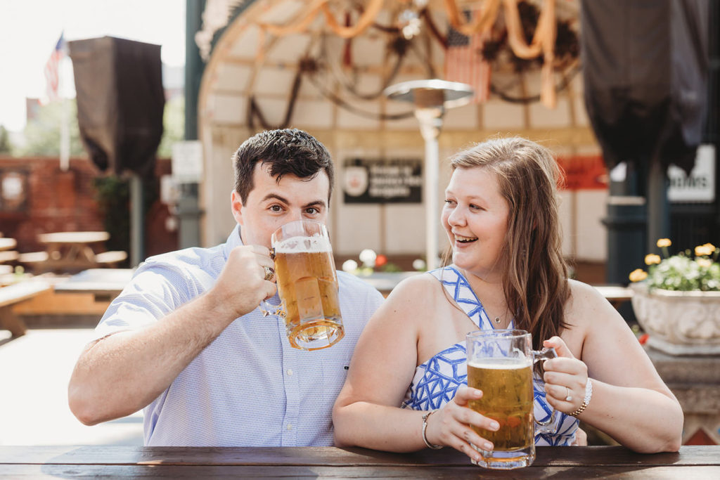 man drinks beer while woman laughs during their Rathskeller engagement session