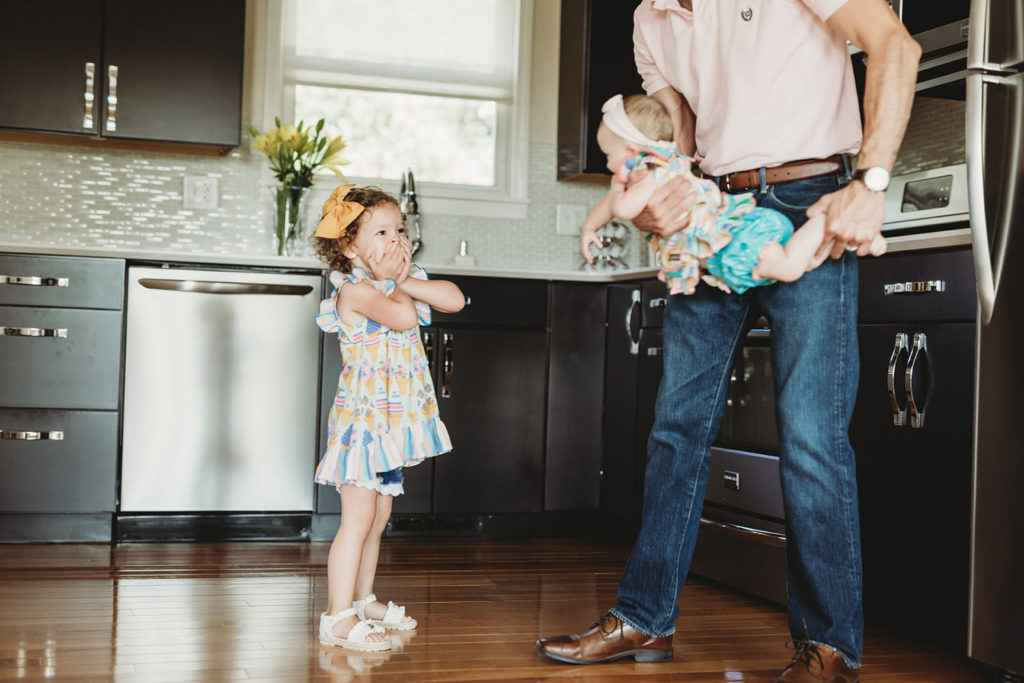lifestyle photography dad swings baby toward daughter in this farmland family photography
