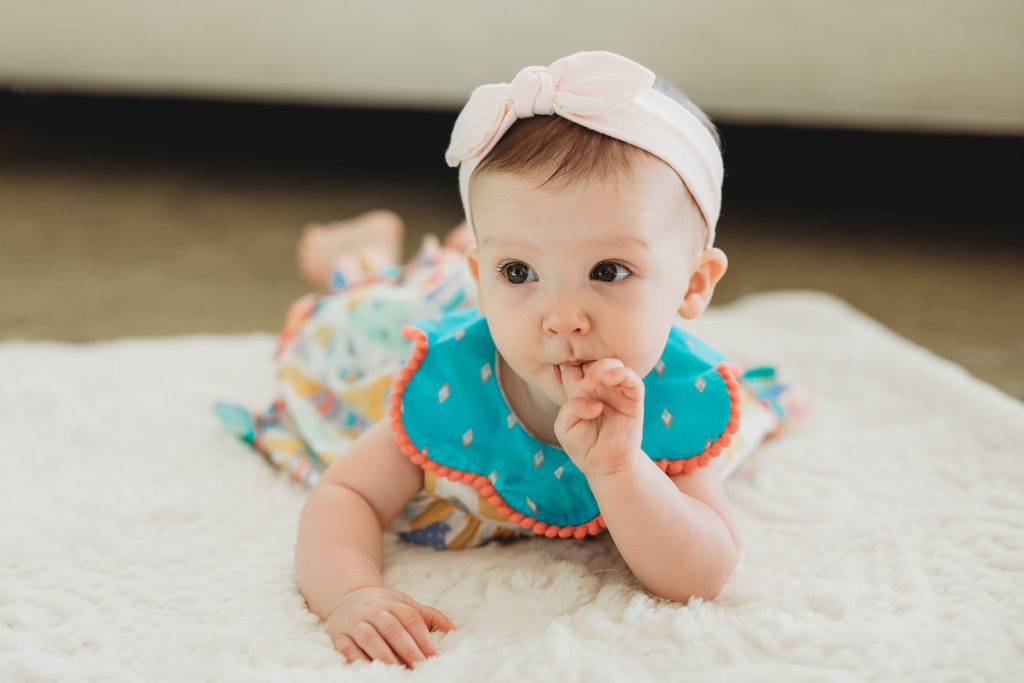 baby girl in blue onesie with pink headband in this parker city family portrait session