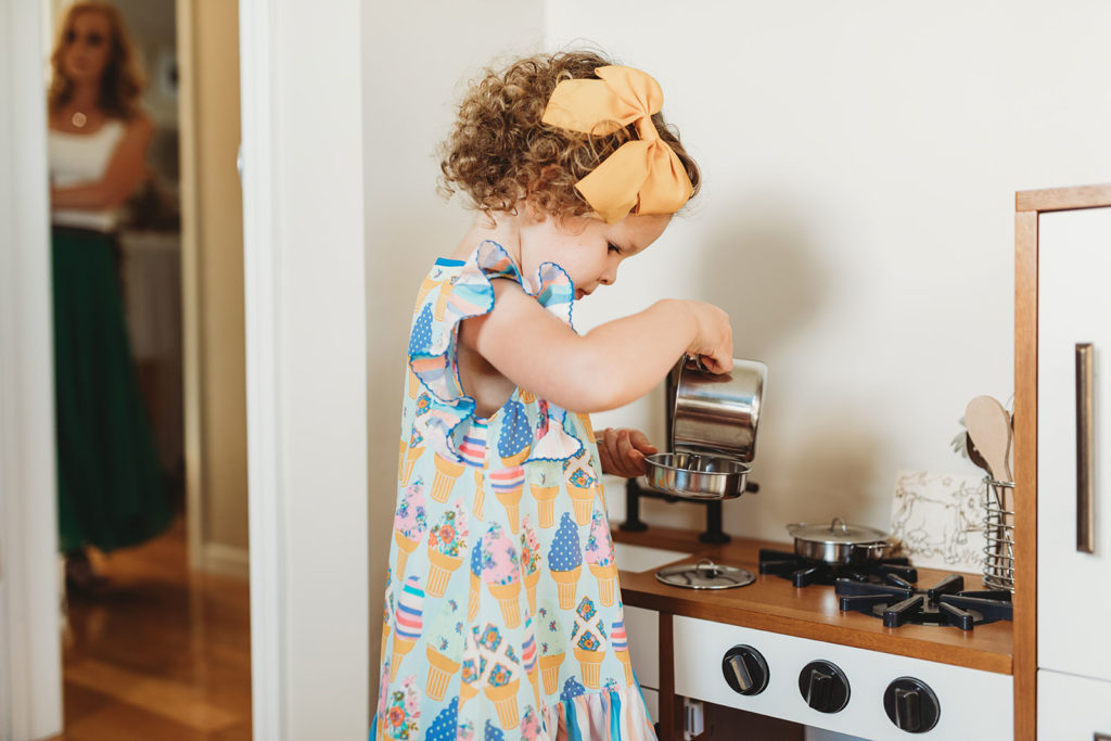 lifestyle family photography in farmland little girl plays in her pretend kitchenette