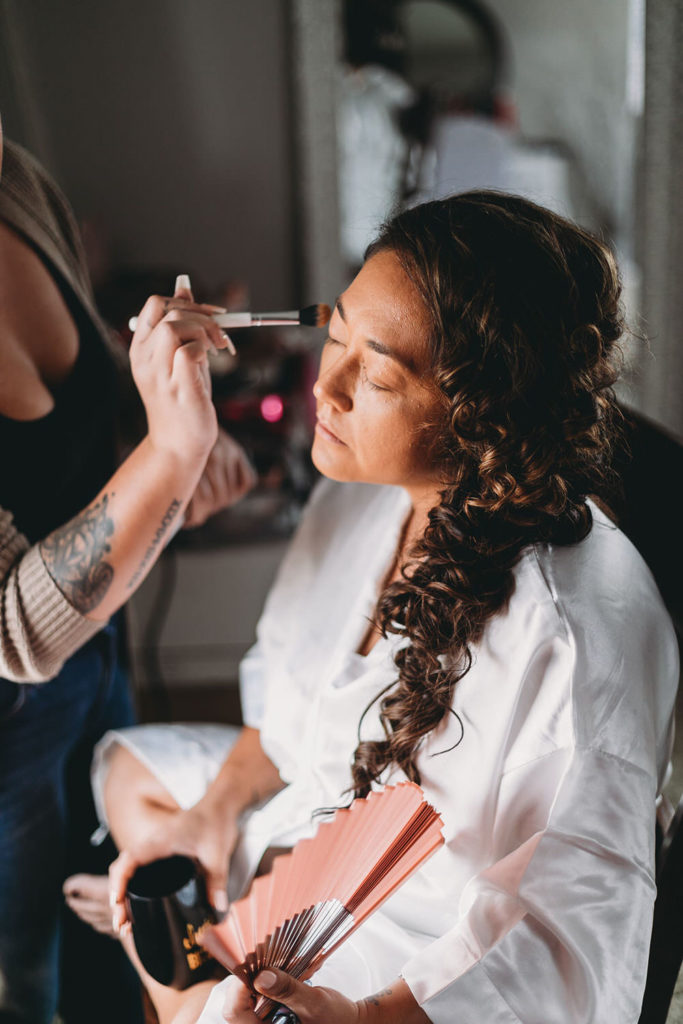 bride getting makeup on in window light at a Franklin Barn Wedding