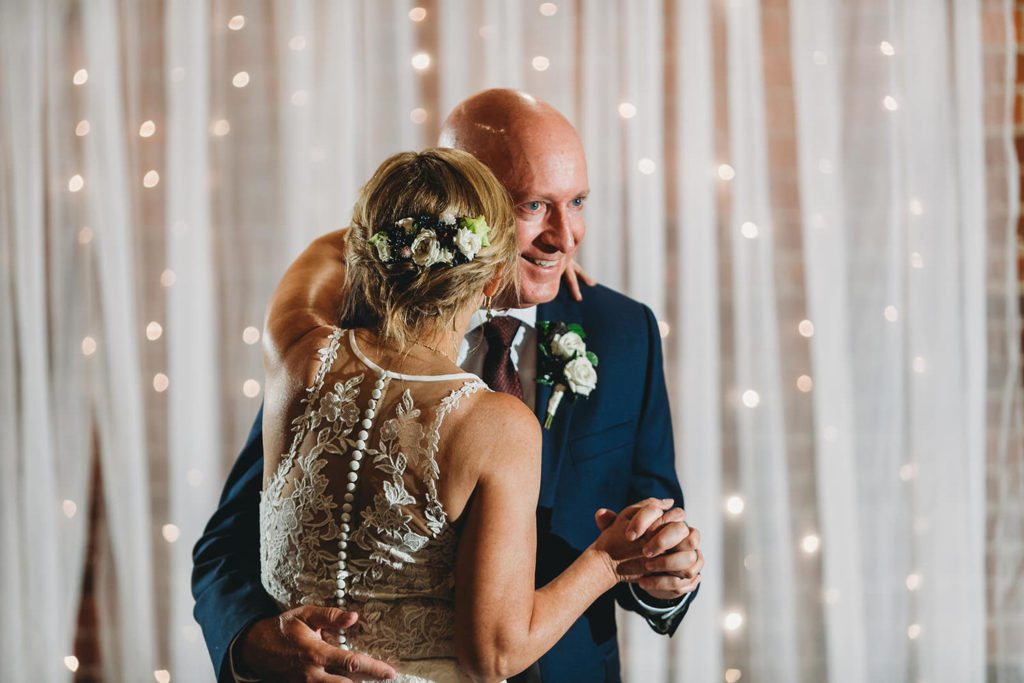 bride and groom dance in front of curtain with lights mill top wedding noblesville