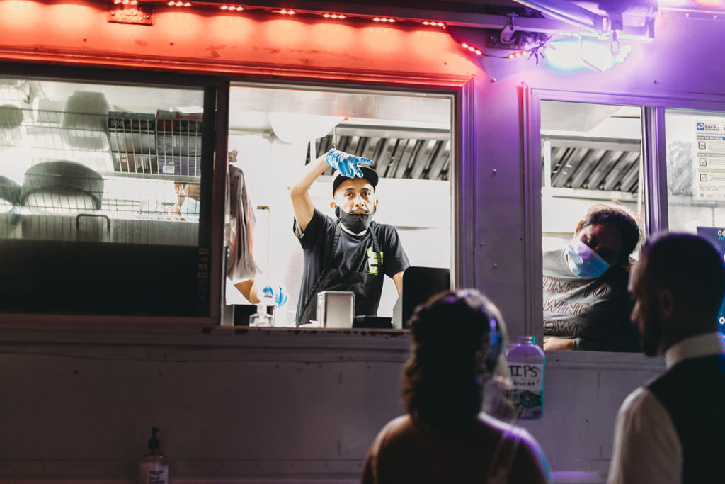 man with blue gloves and black face mask takes orders inside pili's party taco truck at a woolery mill wedding