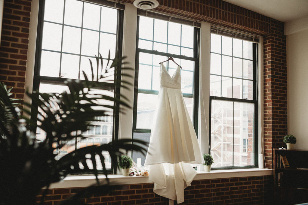 slanted shot of wedding dress in window at an AirBNB before an 1899 wedding