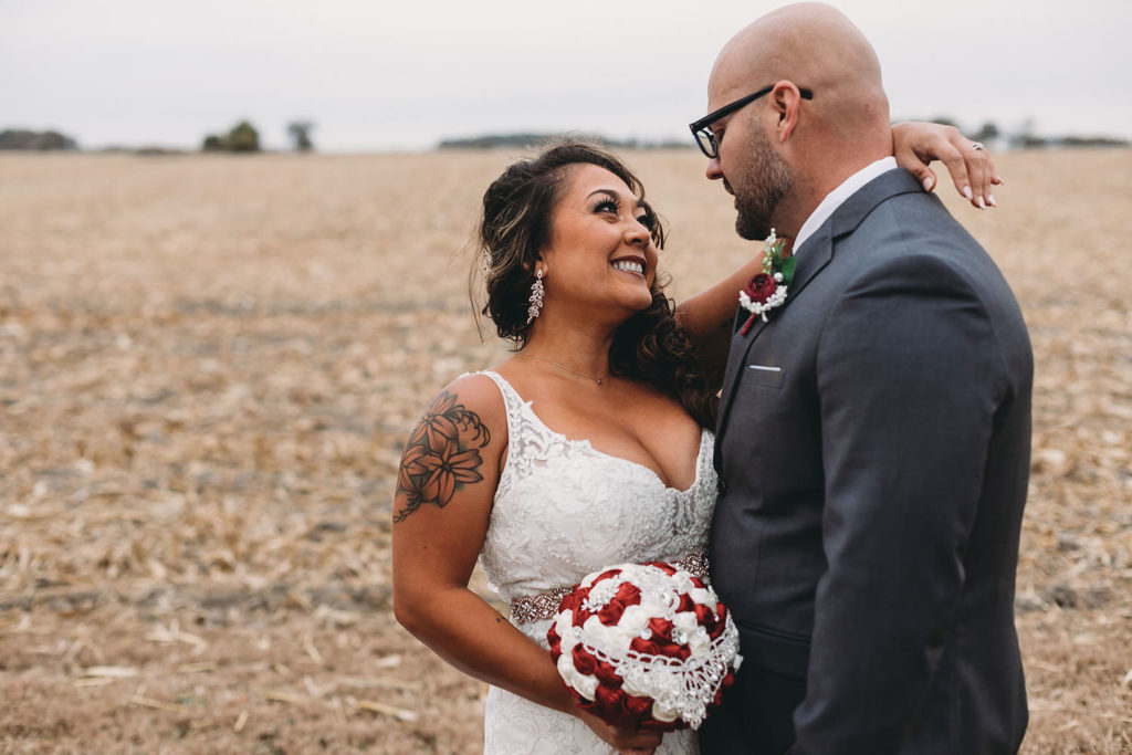 bride smiling and looking at groom in front of a harvested field at a Franklin Barn Wedding