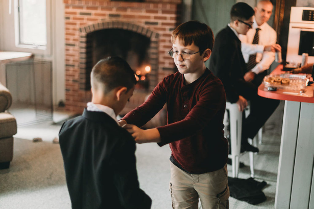 small boy helps another boy get ready at a Franklin Barn Wedding