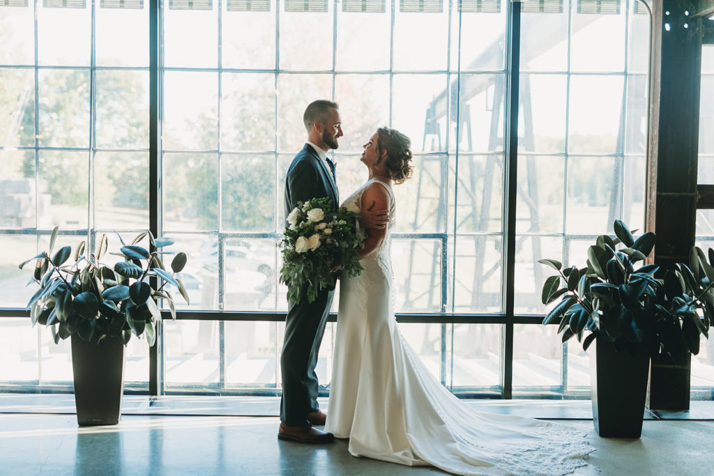 silhouette of bride and groom hugging in front of large windows at a woolery mill wedding