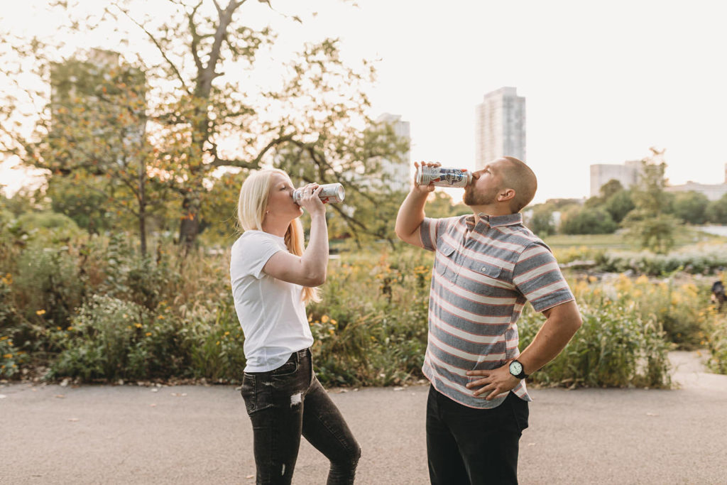 man and woman chug PBRs in the park