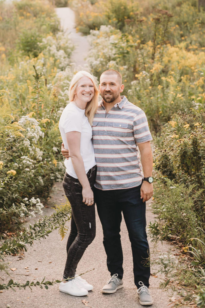 man and woman side hug on endless trail of wildflowers during Lincoln Park engagement photos