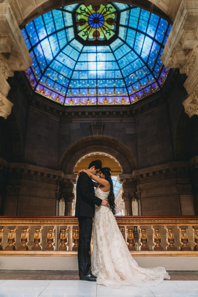 bride and groom touch foreheads in front of stained glass dome at their Indiana Statehouse Elopement
